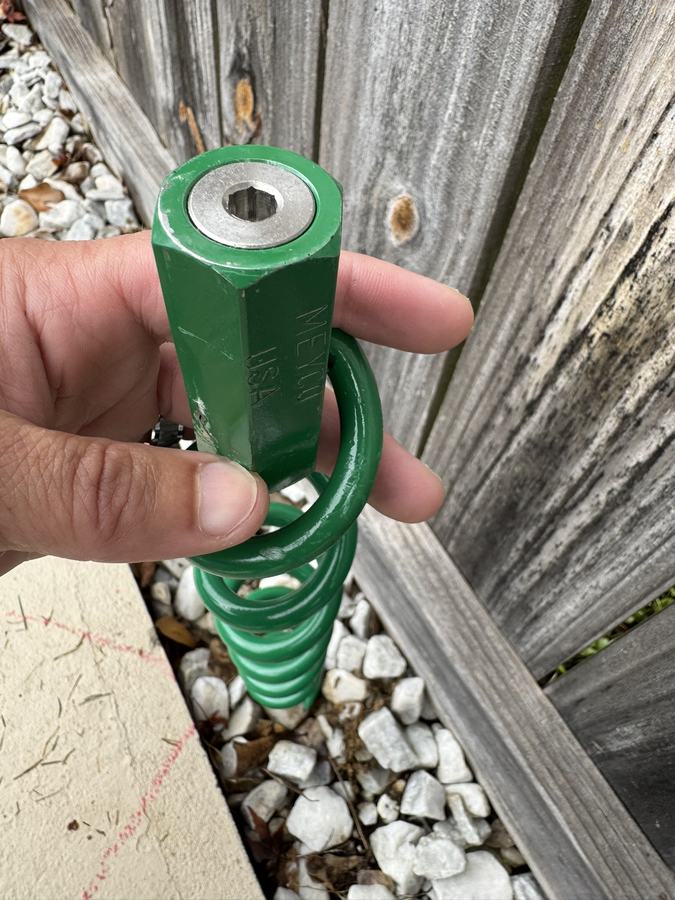 A cover spring with a green sleeve, held up close.