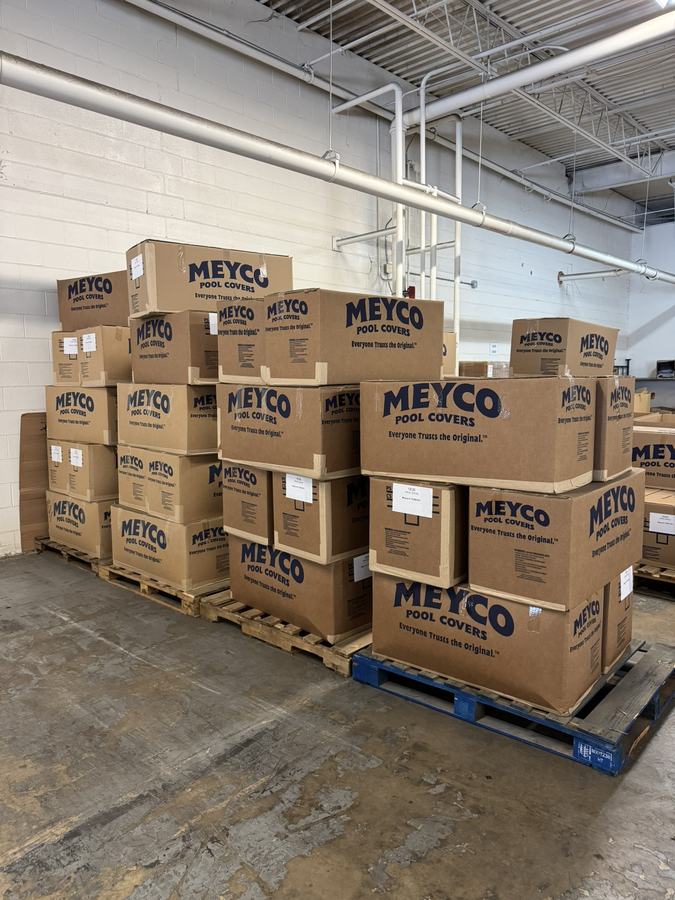 Pallets of boxed Meyco safety covers stacked in a warehouse.