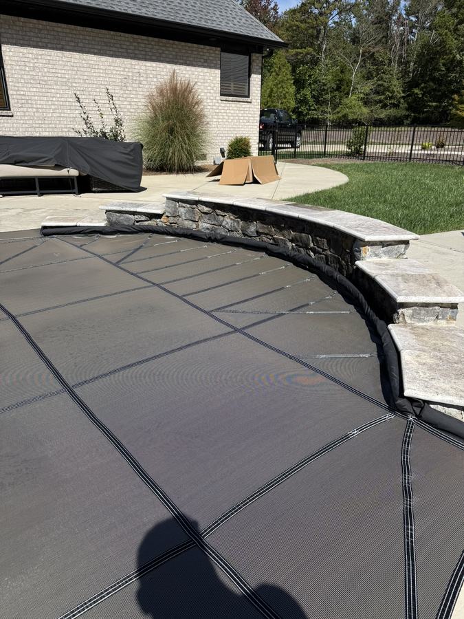 A gray safety cover fitted along a curved, raised stone wall.