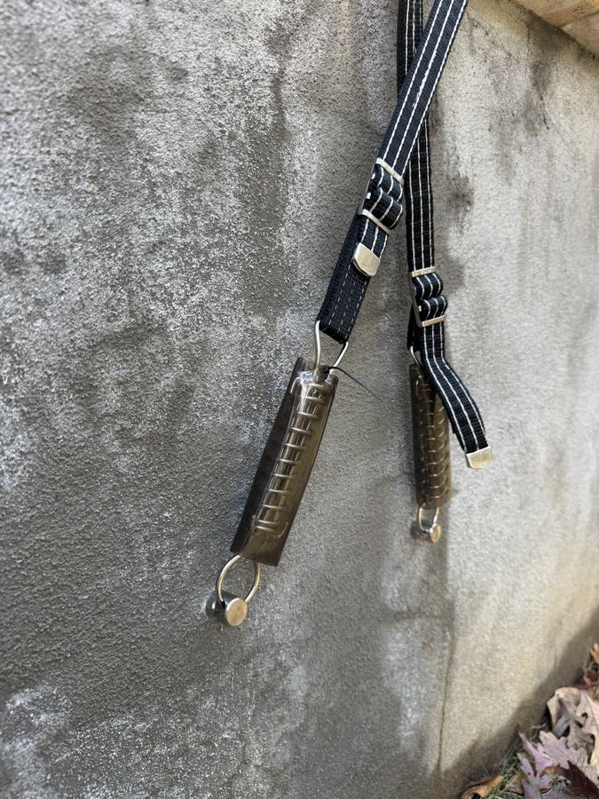 A cover strap and its spring hooked to an anchor on a concrete deck.