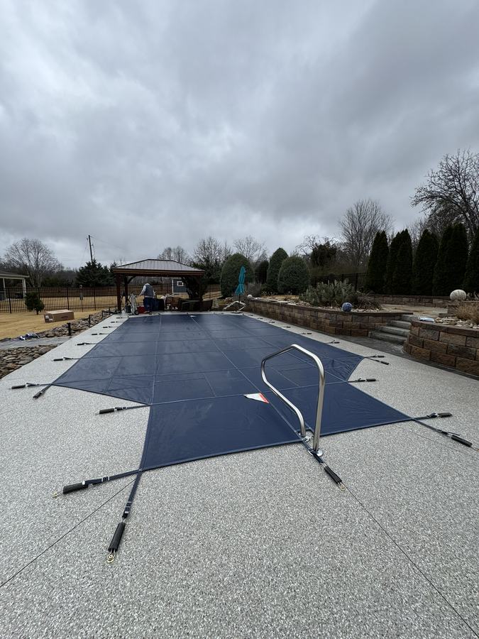 A navy safety cover cut to fit around a pool handrail.