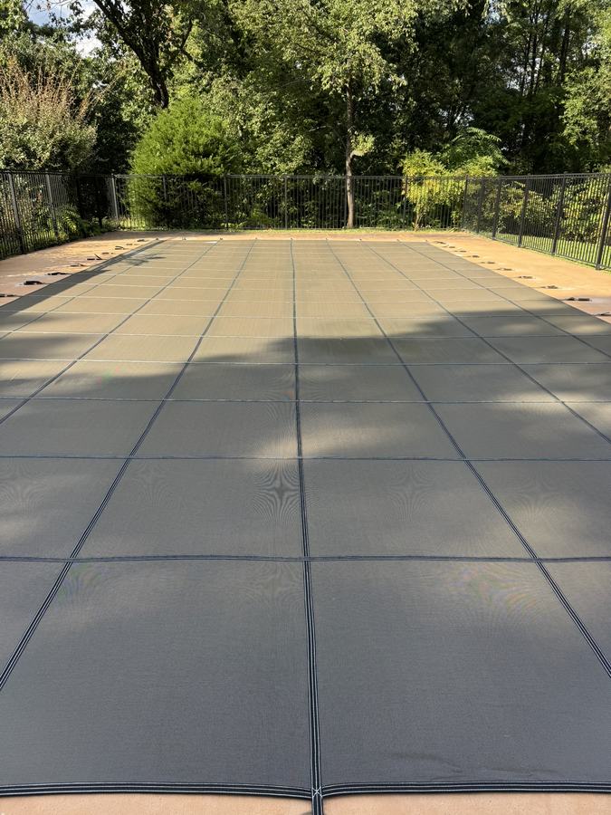 A mocha safety cover pulled tight across a rectangular pool.