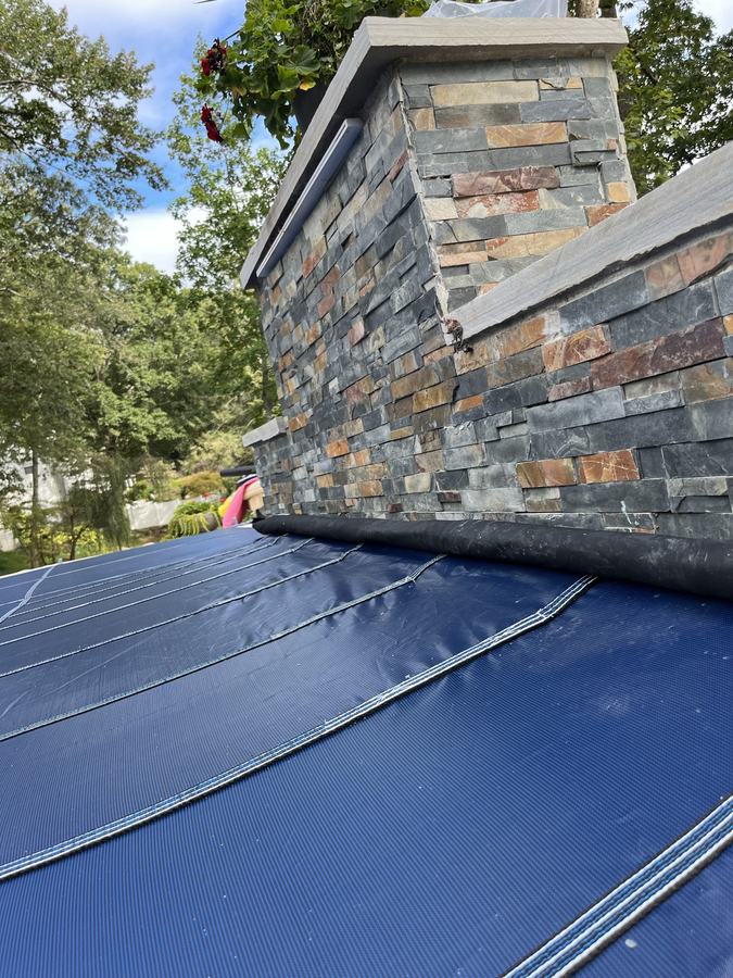 A blue safety cover fitted against a raised stacked-stone wall.