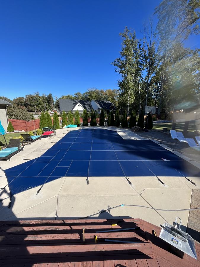 A blue safety cover on a rectangular pool, seen from the steps down to it.